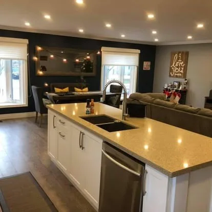 The same living and kitchen area finished with a dark feature wall and recessed lighting