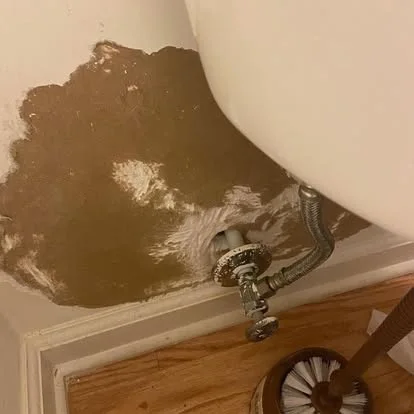 Damaged bathroom wall around the toilet supply connection before repair